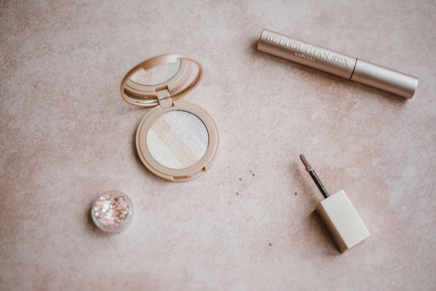 Poudrier et produits de maquillage posés sur une surface claire